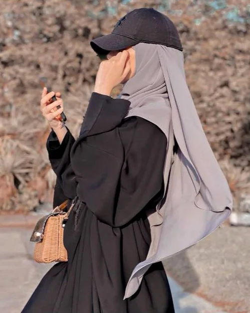 Portrait d’Amandine Santi, webdesigner WordPress, de profil en hijab et casquette, téléphone à la main